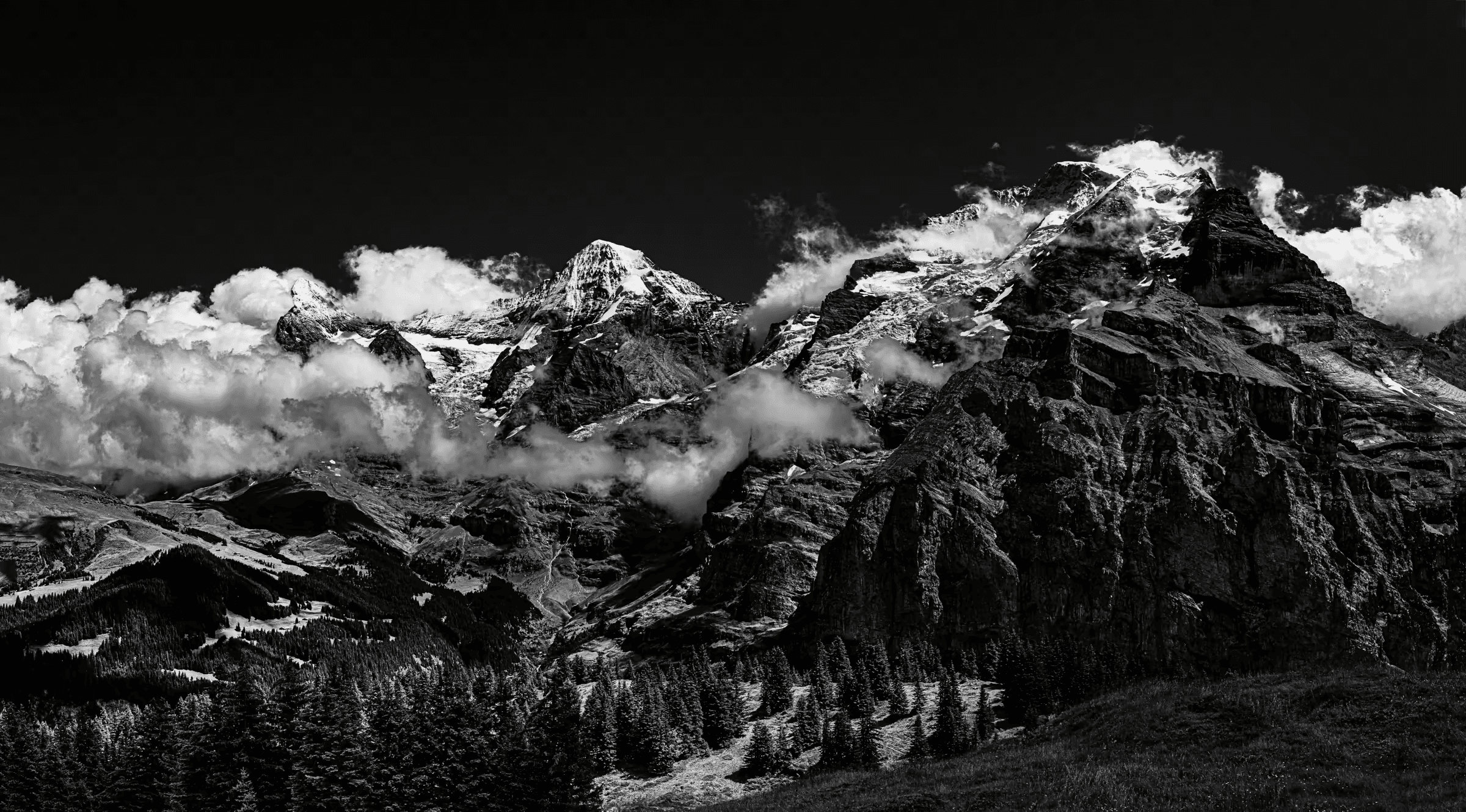 Black and white landscape photograph of the Eiger, Mönch, and Jungfrau mountains in the Swiss Alps, viewed from Mürren.