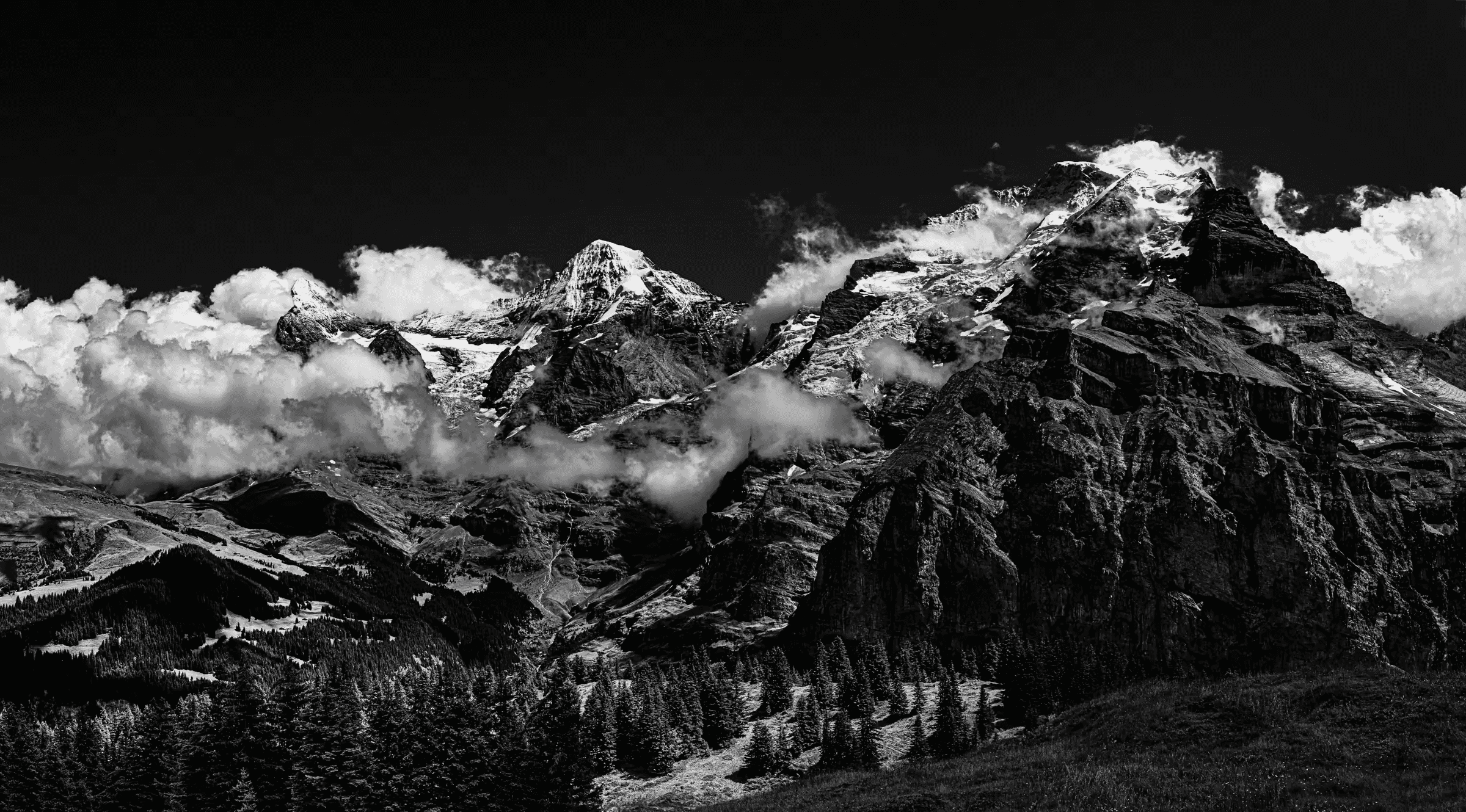 Black and white landscape photograph of the Eiger, Mönch, and Jungfrau mountains in the Swiss Alps, viewed from Mürren.