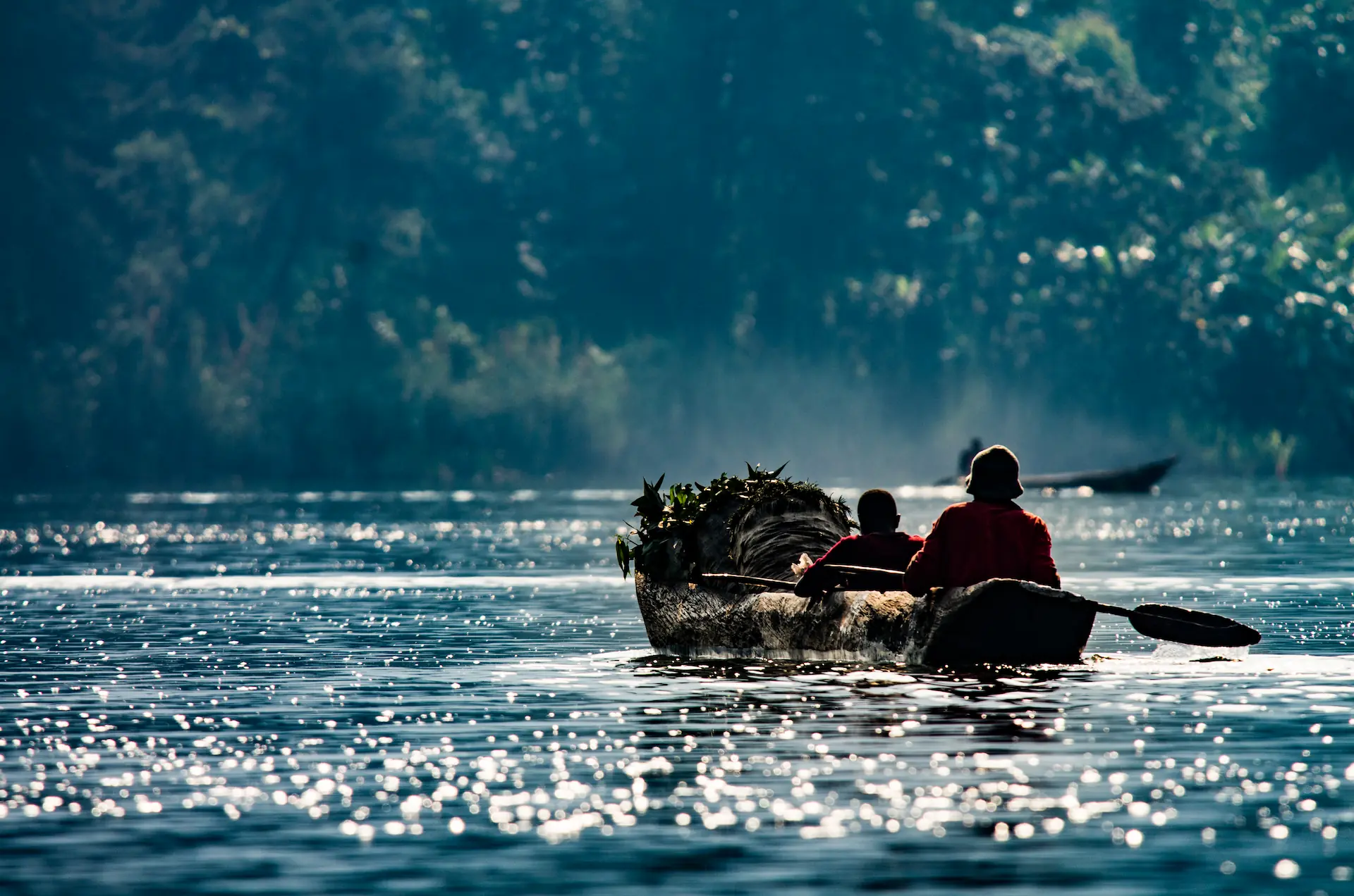 Boat on Lake Bunyonyi, Uganda Traditional boat crossing shimmering water on Lake Bunyonyi, Uganda.