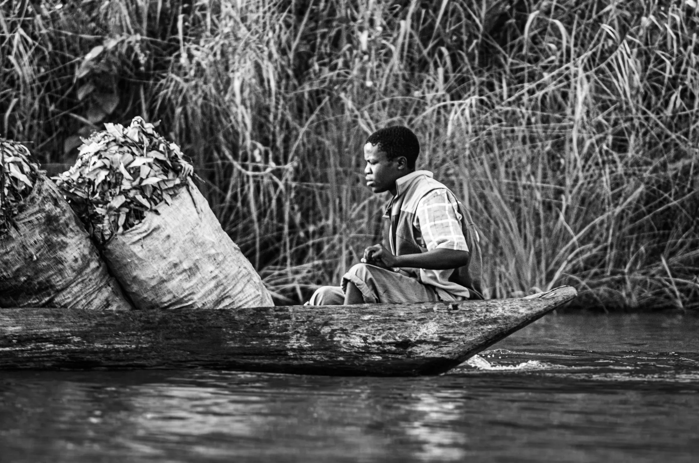 Black-and-white profile of a man transporting tea on Lake Bunyonyi, Uganda.
