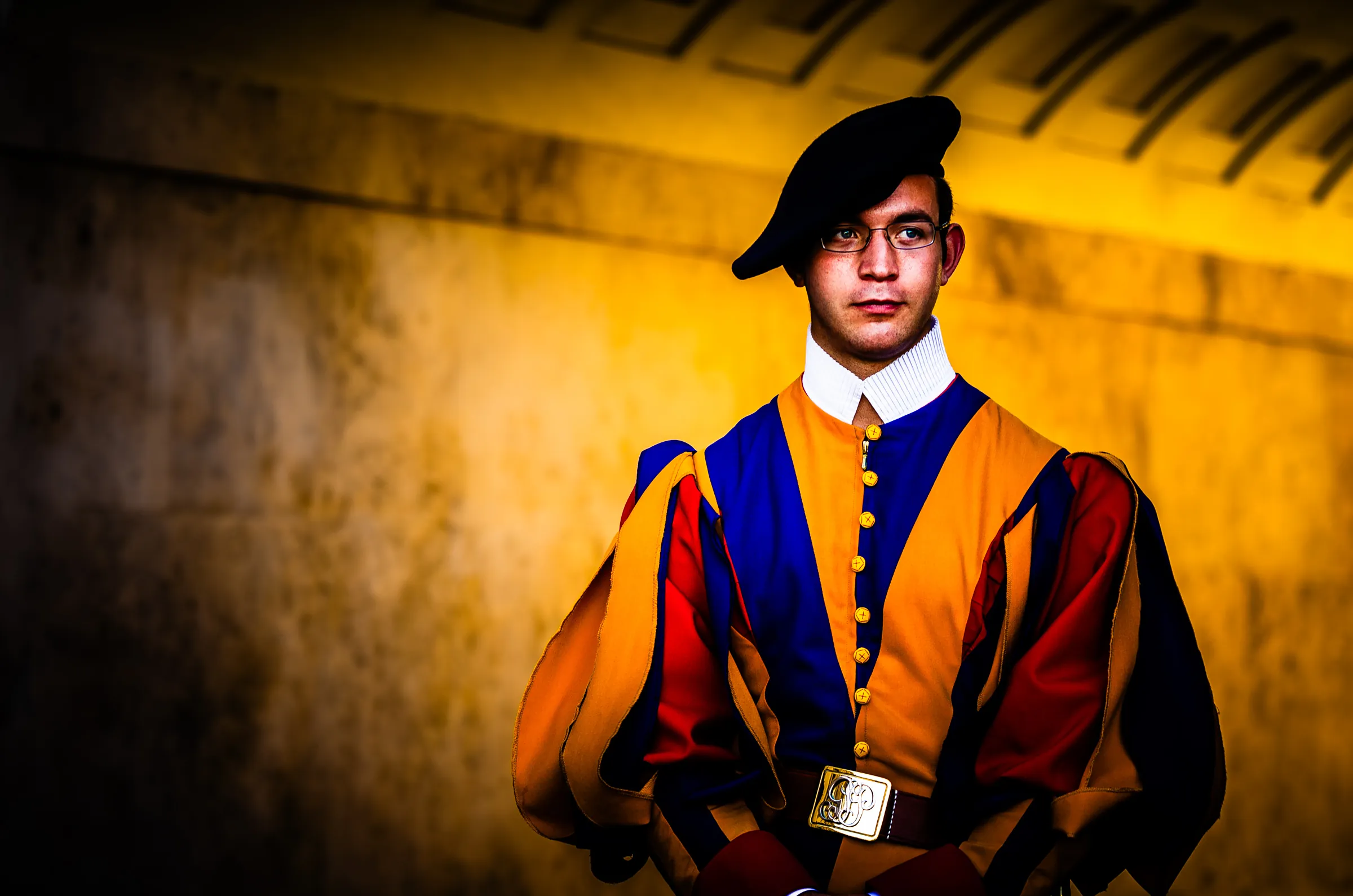 Color portrait of a Swiss Guard standing duty in Vatican City, wearing the traditional colorful Renaissance uniform and black beret.