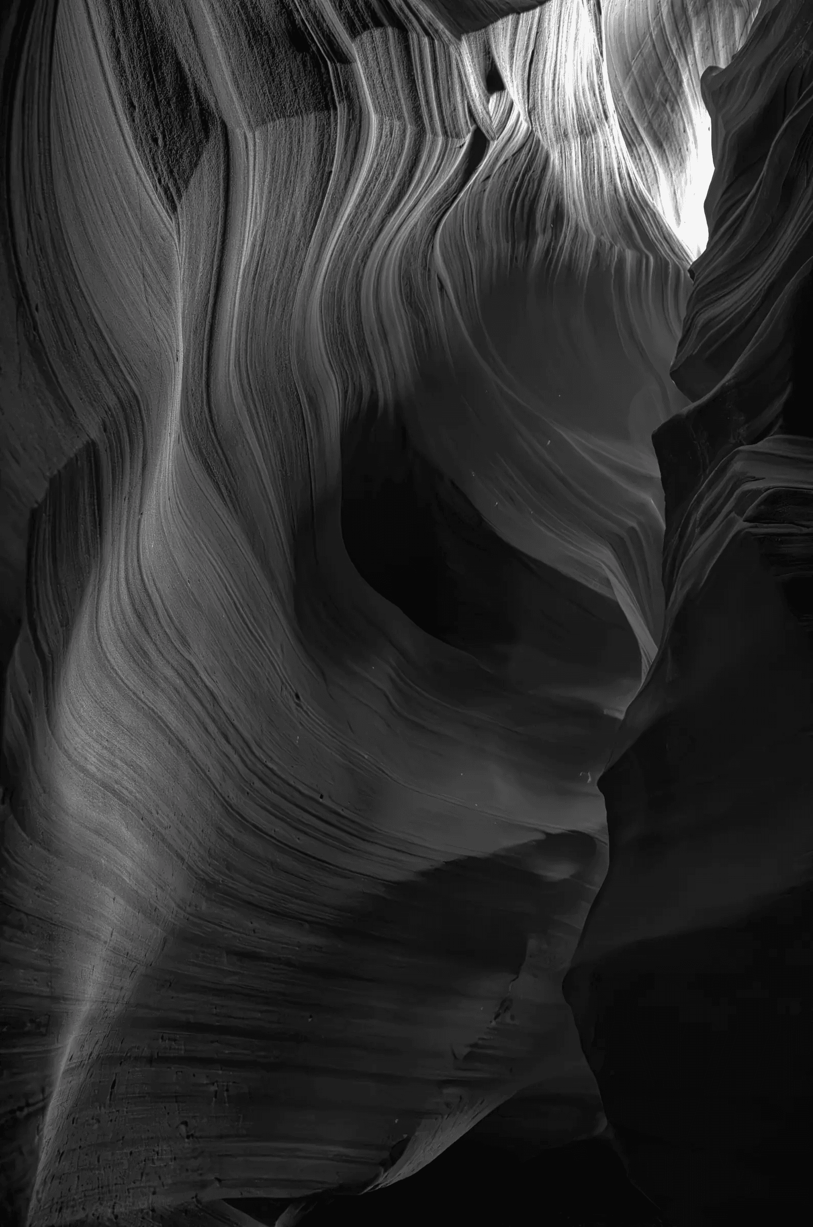 Through Time Interior of a slot canyon with sweeping, layered sandstone walls lit from above, shown in black and white
