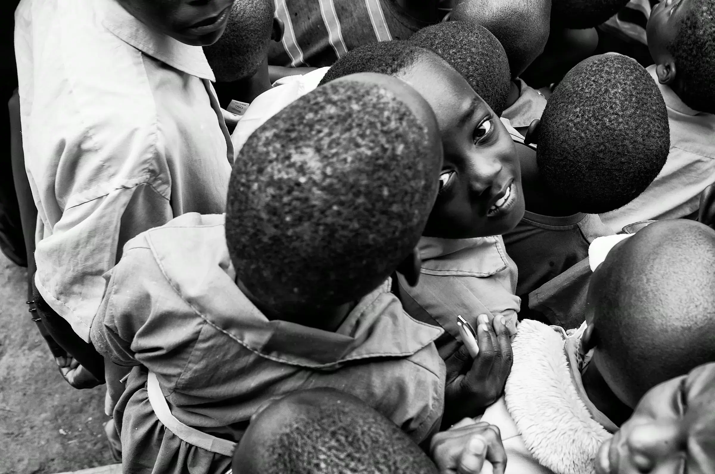 Black-and-white photograph of a group of children in Uganda looking up.