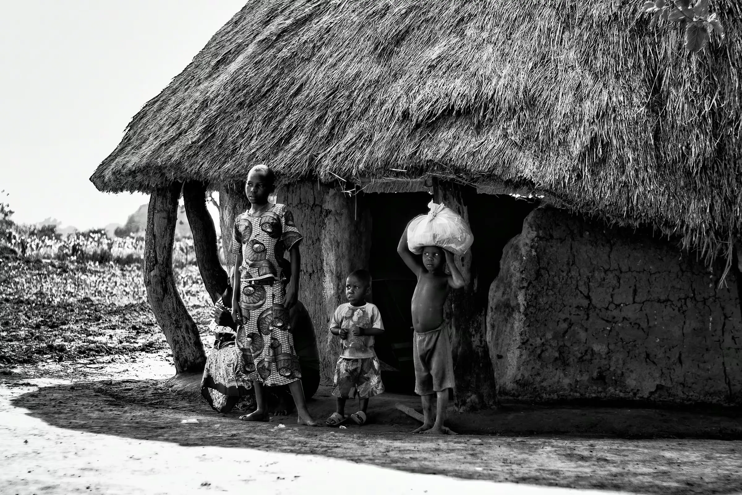 Ugandan Family: Life in a Rural Village A Ugandan family standing outside their traditional mud hut with a thatched roof.