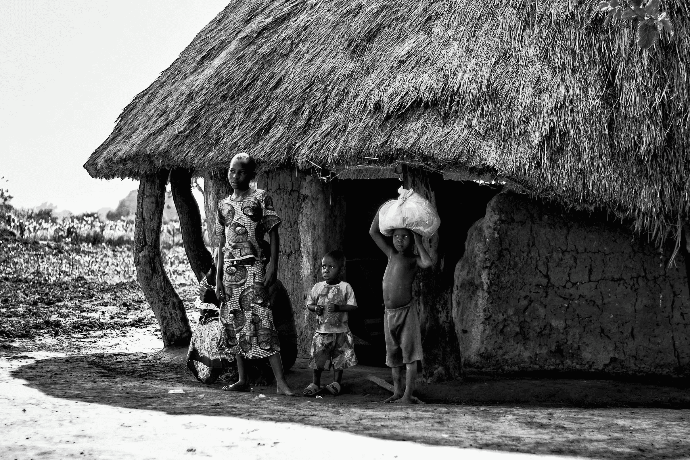 Ugandan Family: Life in a Rural Village A Ugandan family standing outside their traditional mud hut with a thatched roof.