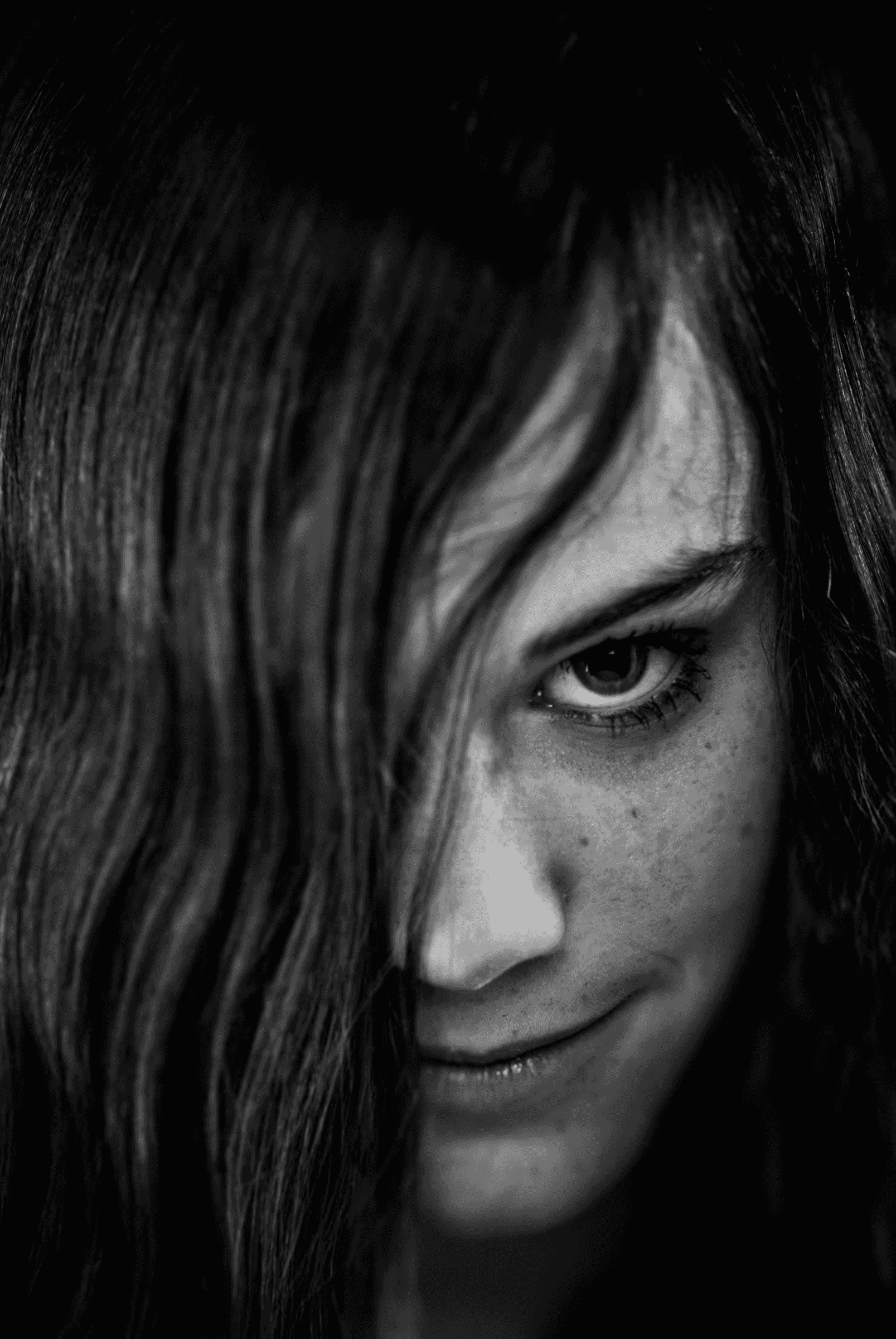 Hidden Gaze: Monochrome Portrait Black and white portrait of a woman with long hair partially covering her face.