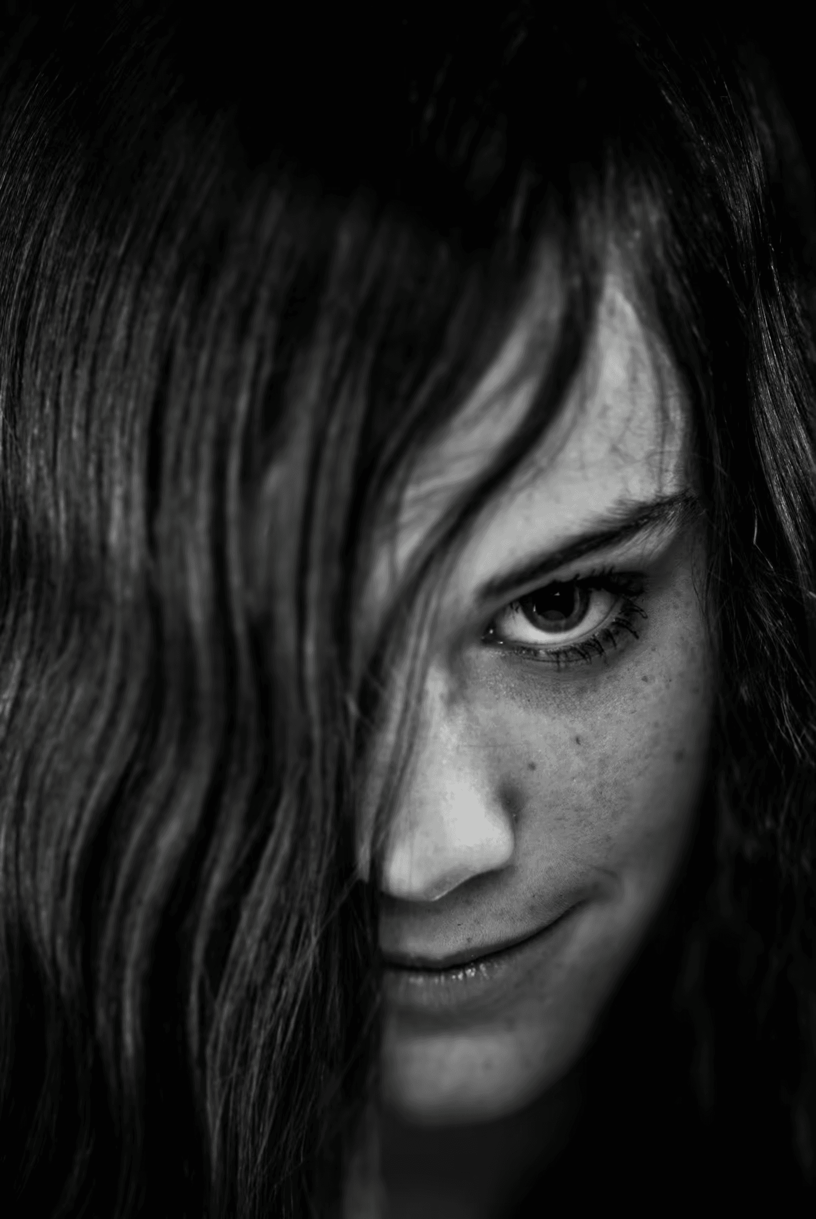 Black and white portrait of a woman with long hair partially covering her face.