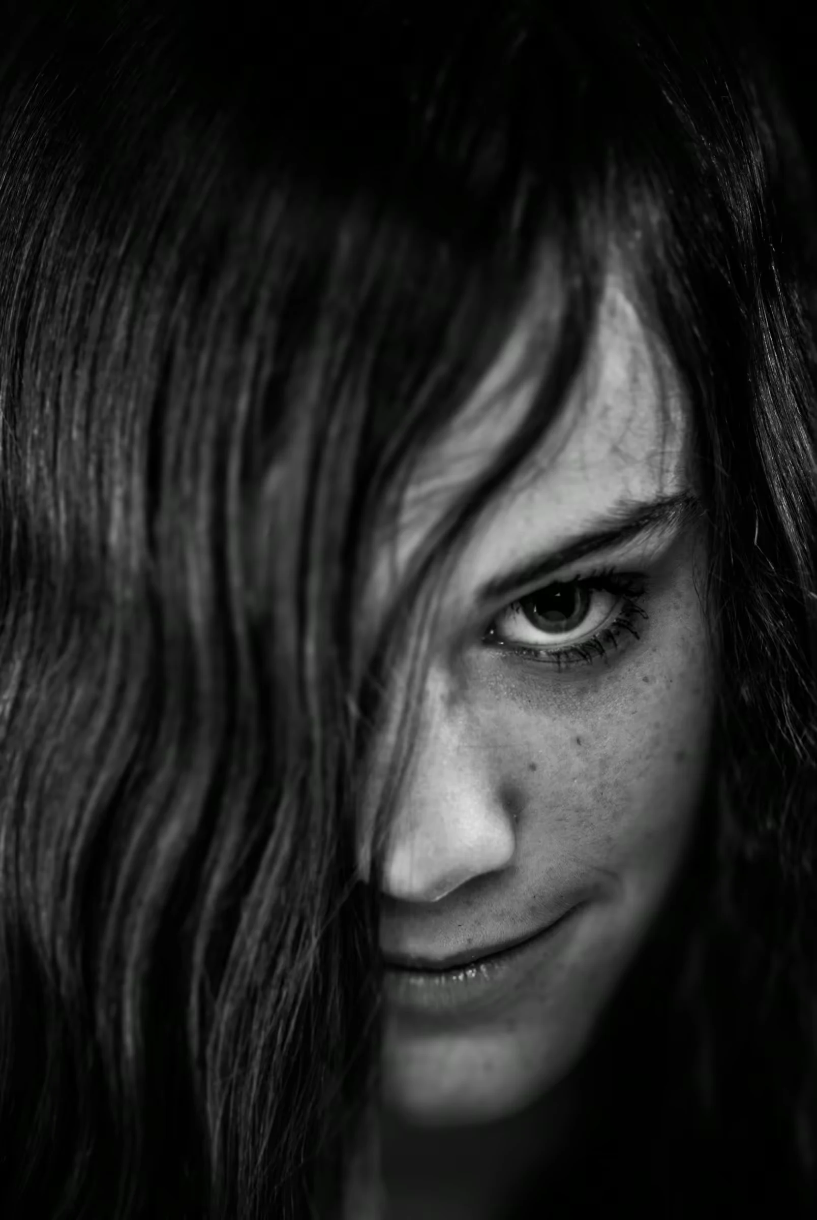 Black and white portrait of a woman with long hair partially covering her face.