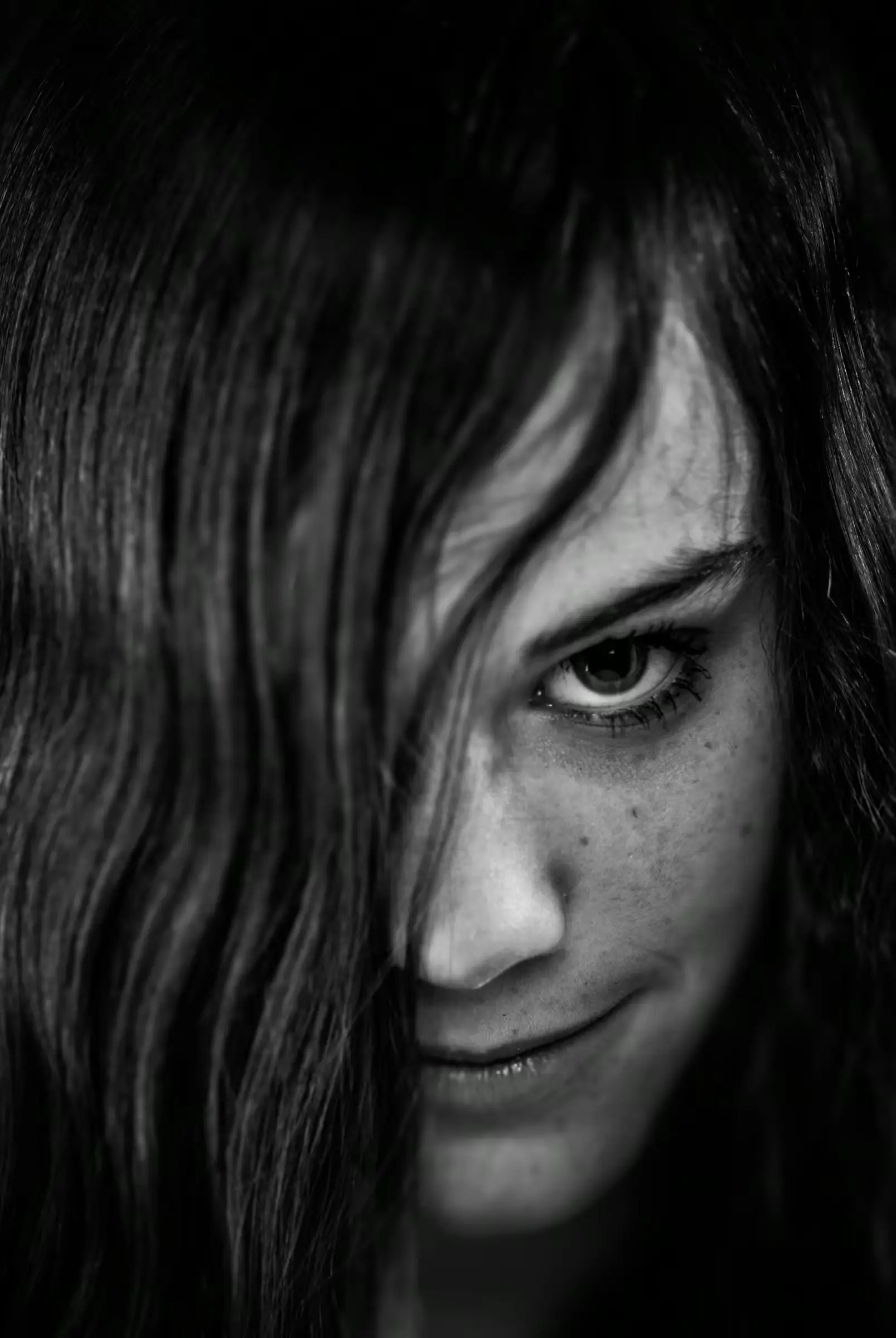 Black and white portrait of a woman with long hair partially covering her face.