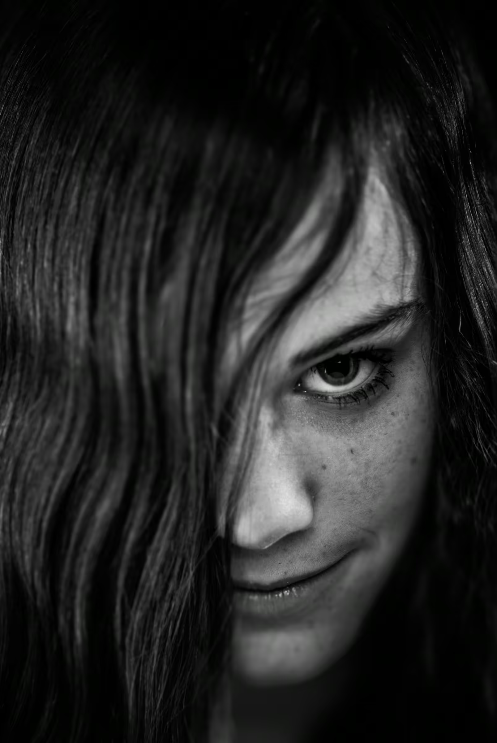 Black and white portrait of a woman with long hair partially covering her face.
